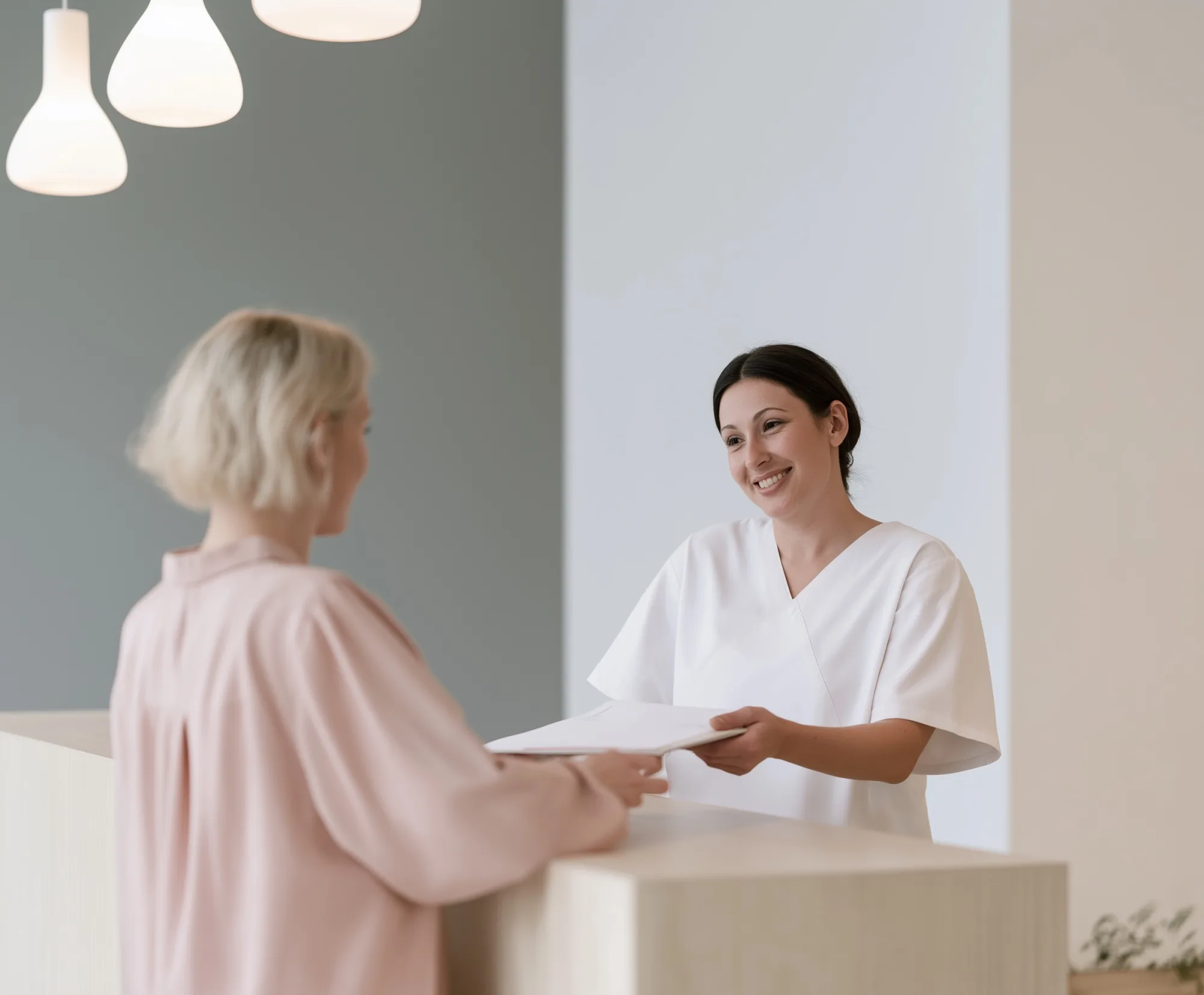 A receptionist handing a form to a patient at the front desk